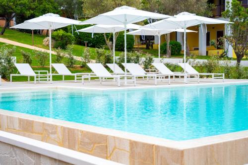 a pool with white lounge chairs and umbrellas at Felix Hotels - Residence Hotel Costa Serena in Palau