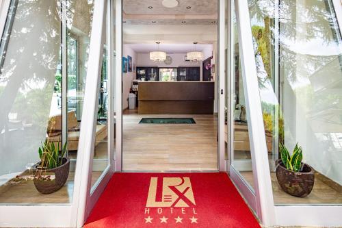 un tapis rouge à l'entrée d'un magasin avec des plantes dans l'établissement Hotel Rex, à Lignano Sabbiadoro