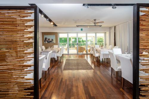 une salle à manger avec des tables blanches et des chaises blanches dans l'établissement Hotel Rex, à Lignano Sabbiadoro