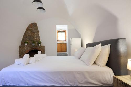 a bedroom with a large white bed with a fireplace at Avgonyma Square Nest in Avgonyma
