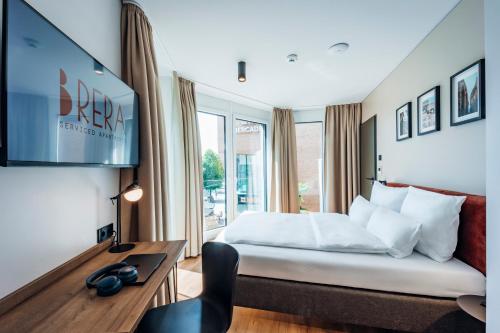 a hotel room with a bed and a desk and a tv at Brera Serviced Apartments Böblingen Sindelfingen in Böblingen