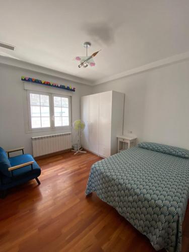 a bedroom with a bed and a blue chair and a window at Casa Rural Goñi in Cabañas de Ebro