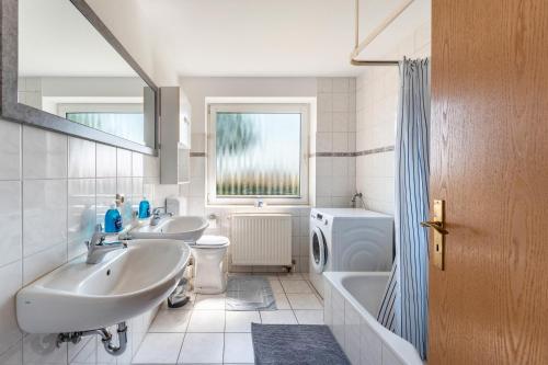 a bathroom with two sinks and a tub and a toilet at Ferienhaus Sonja in Waabs