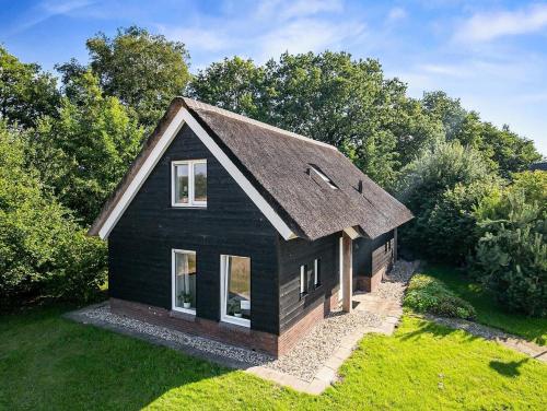 a black house with a brown roof on a yard at Buitengoed Rheelanden in Ansen