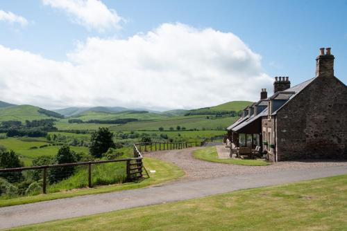 an old house on a hill with mountains in the background at College Cottage in Wooler