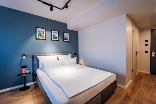 a bedroom with a large bed with a blue wall at Brera Serviced Apartments Böblingen Sindelfingen in Böblingen