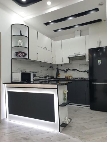 a kitchen with white cabinets and a black refrigerator at VIALPI Guest House in Gyumri