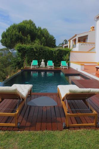 a swimming pool with two lounge chairs and a table at Casa da Barragem - Castelo de Bode in Castelo do Bode