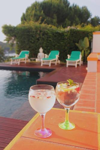 two wine glasses sitting on a table next to a pool at Casa da Barragem - Castelo de Bode in Castelo do Bode