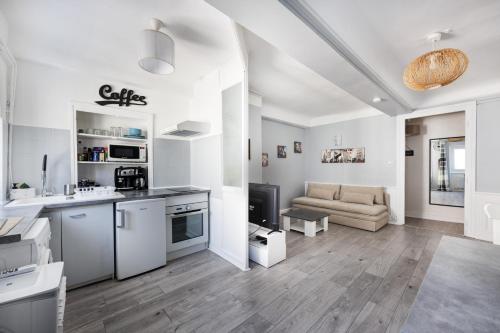 Il comprend une cuisine blanche et un salon avec un canapé. dans l'établissement L'hyper centre terreaux 45m2 équipé CLIM, à Lyon