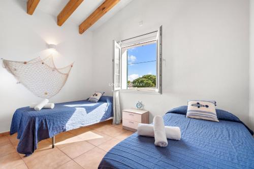 two beds in a room with a window at Villa Vergara in Cala en Porter