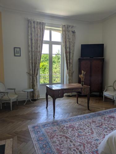 un salon avec une table et une grande fenêtre dans l'établissement Chambre d'hôte - petit château à la campagne, à Saint-Aubin-Epinay
