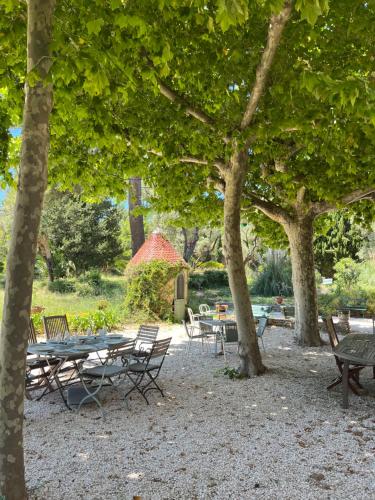 a group of tables and chairs in a park with trees at Villa Magdala Arts & Résidence in Hyères