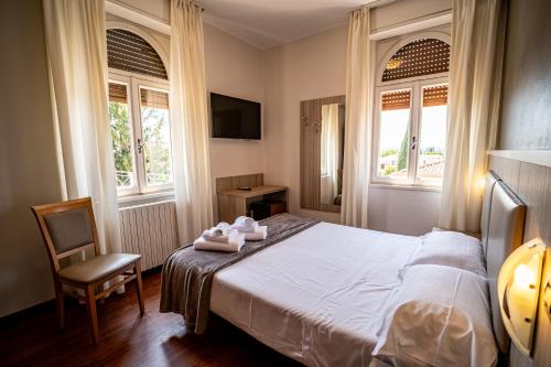 a bedroom with a bed with a chair and two windows at Hotel Gardenia Sirmione in Sirmione