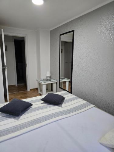 a bedroom with a bed with two pillows and a mirror at Vikendica Fruškogorski kutak - Fruška Gora in Čerević