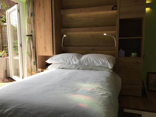 a large white bed with a wooden headboard and a rainbow at The Barn Seaside Studio - Sleeps 2 & Hot Tub in South Hayling