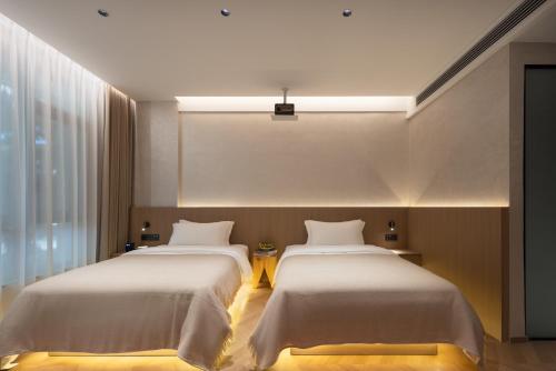 two beds in a hotel room with white sheets at YujianHotel in Jingdezhen