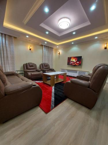 a living room with couches and a table and a tv at Nanyuki House in Nanyuki