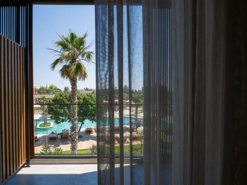a room with a view of a resort with a palm tree at Portes Theros in Nea Potidaea