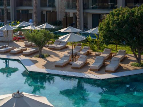 an empty swimming pool with lounge chairs and umbrellas at Portes Theros in Nea Potidaea