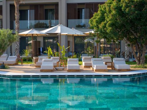 a hotel pool with lounge chairs and umbrellas at Portes Theros in Nea Potidaea