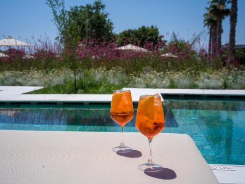 two wine glasses sitting on a table next to a swimming pool at Portes Theros in Nea Potidaea