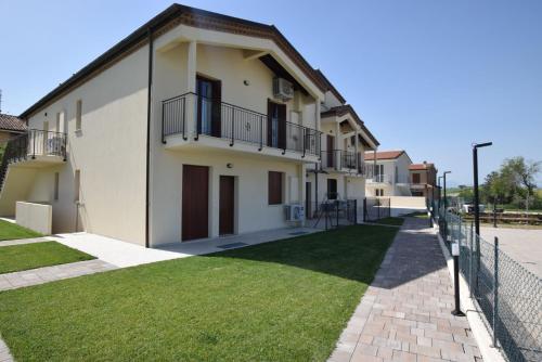 a building with a fence next to a grass yard at Casa In Collina in La Figurina