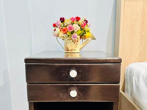 a vase of flowers sitting on top of a dresser at สวนไมตรีจิต รีสอร์ท in Ban Khlong Si