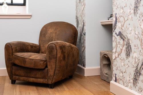 a brown chair sitting in a room next to a wall at The Highland Club in Fort Augustus
