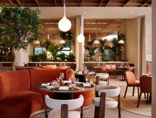 Un restaurante con mesas, sillas y plantas. en Arba Resort, Valamar Collection, en Rab