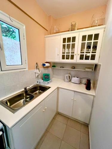 a kitchen with white cabinets and a sink and a window at Fiskardo Beach Apartments in Fiskardho
