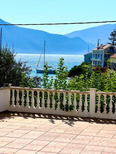 a white fence with a sail boat in the water at Fiskardo Beach Apartments in Fiskardho