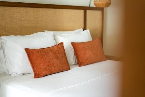 a bed with white pillows and two orange pillows at Nostos Beach Boutique Hotel in Balíon