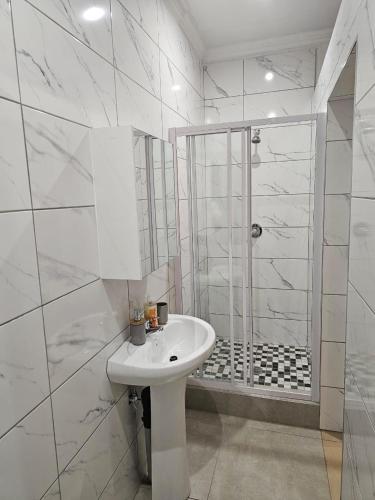 a white bathroom with a sink and a shower at WiseStar Guest House in Johannesburg