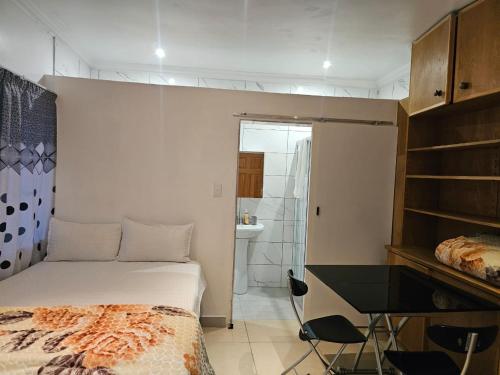 a bedroom with a bed and a desk and a bathroom at WiseStar Guest House in Johannesburg