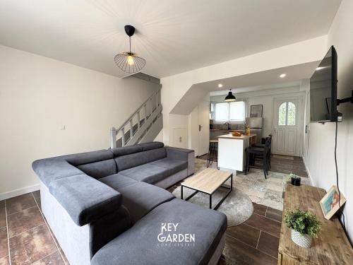 a living room with a gray couch and a kitchen at Maison calme 10 min from Disneyland in Villiers-sur-Morin