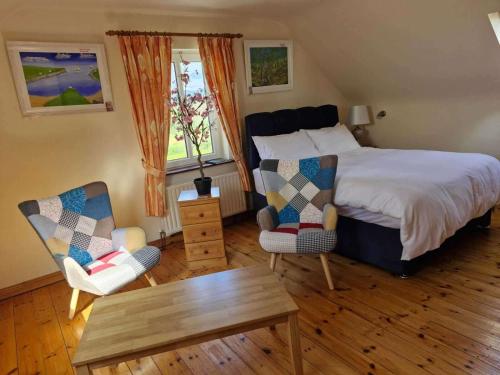 a bedroom with a bed and two chairs and a table at Villa Rose - Sleeps 2 & Stunning Seaside Views in Cahersiveen