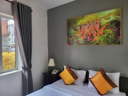 a bedroom with a bed with a painting on the wall at Sun Chakra Boutique Hotel - 50m to Museum & Royal Palace & Walking street in Phnom Penh