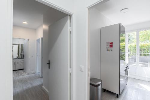 un couloir aux murs blancs et une porte coulissante en verre. dans l'établissement 2 Bedroom apartment Galmy Val d'Europe, à Chessy