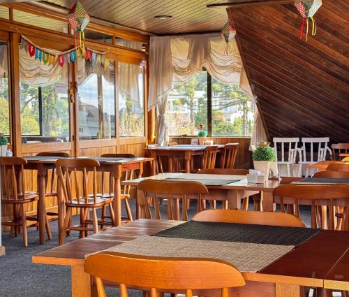 een restaurant met houten tafels en stoelen en ramen bij Hotel Tissiani Canela in Canela