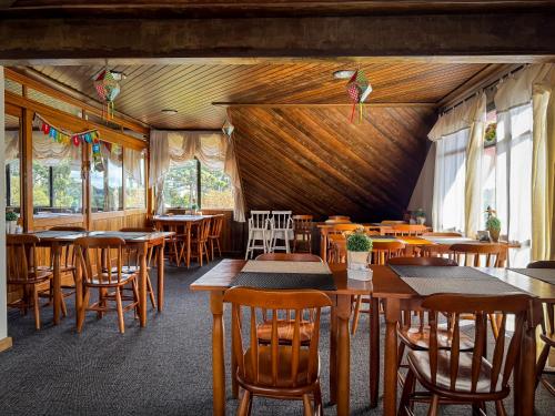 een restaurant met houten tafels en stoelen en ramen bij Hotel Tissiani Canela in Canela