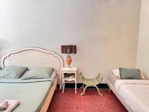 a bedroom with two beds and a table with a lamp at Villa Magdala Arts & Résidence in Hyères