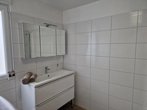 a white bathroom with a sink and a mirror at Appartement rénové Au Rain Grébatte avec terrasse in La Croix-aux-Mines