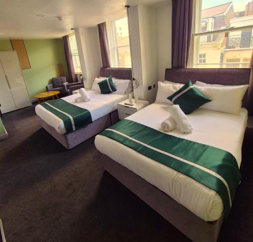 a hotel room with two beds with green and white sheets at Hotel 105 in Liverpool