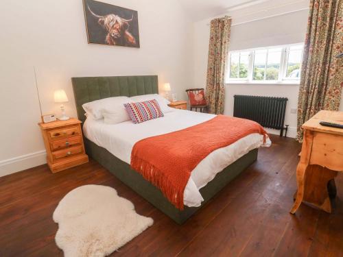 a bedroom with a bed and a desk and a window at Lavender Cottage in Helston
