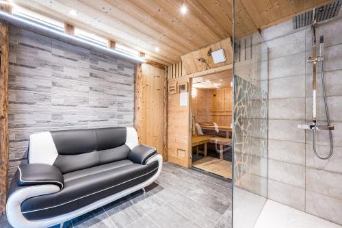 un canapé en cuir noir dans une salle de bain avec douche dans l'établissement Chalet - Le crey rond, à Valloire