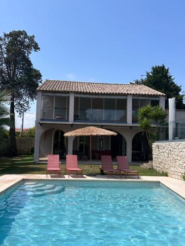 une maison dotée d'une piscine avec des chaises et un parasol dans l'établissement Villa Miliana, au Cannet