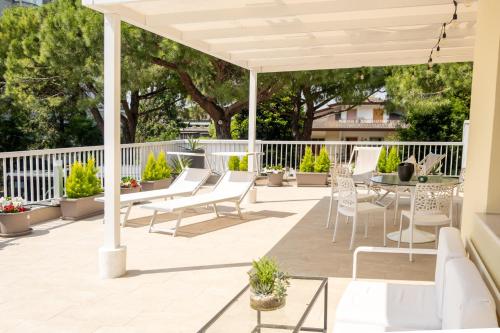 Terrace Apartment -M3 Apartments في ليدو دي يسولو: فناء به كراسي وطاولات ومظلة بيضاء