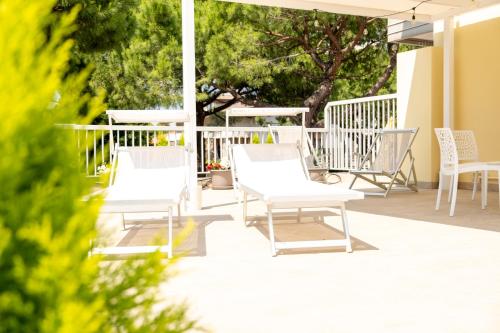 Terrace Apartment -M3 Apartments في ليدو دي يسولو: مجموعة من الكراسي البيضاء على الفناء