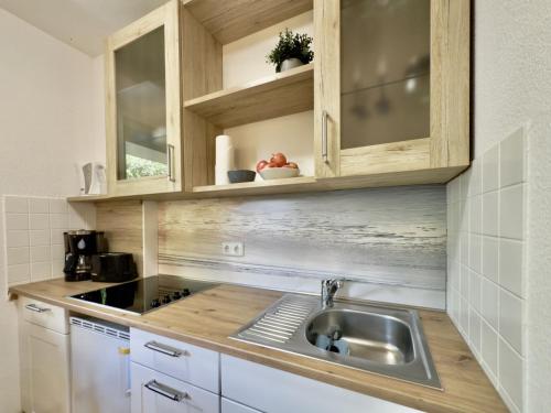 a kitchen with a sink and wooden cabinets at Gästehaus Vogel - Silbermöwe in Horumersiel